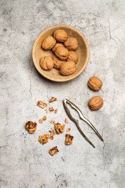 Walnuts in a wooden bowl and a nutcracker on a marble kitchen countertop