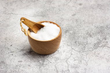 Tahta bir kasede, gevrek içinde tuz. Mutfak tezgahında tahta bir kaşık ve fotokopi alanı var.