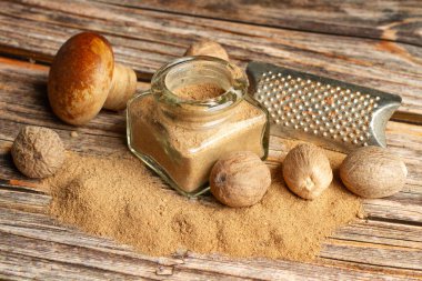 Nutmegs ve toz hindistan cevizi kristal bir şişede ve tahta bir kaşıkta tahta bir masada