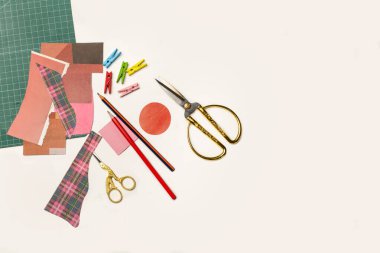 Altın kaplama leylek makasları, kalemler ve renkli kağıtlar kopya alanı olan beyaz bir arkaplanda.