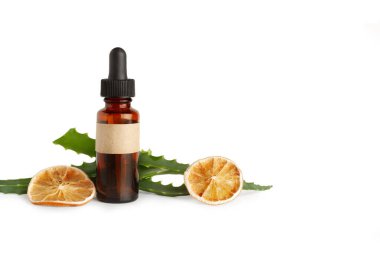 Kahverengi şişede bir damlatıcı, aloe vera yaprakları ve beyaz arka planda kurutulmuş portakal dilimleri.