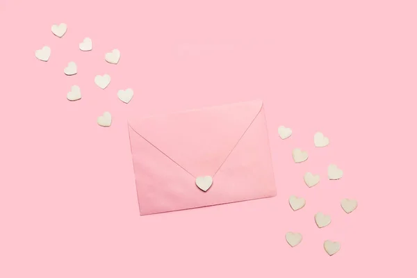 A pink envelope and white small hearts on a pink background