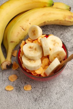 Bir avuç muz ve kahvaltılık mısır gevreği ve mermer mutfak tezgahında muz dilimleri.