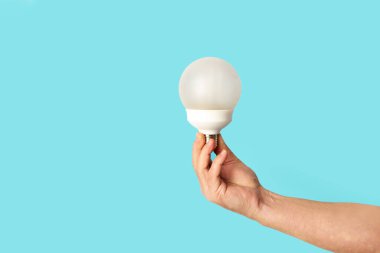 Adamın elinde mavi arkaplanda fotokopi alanı olan bir ampul var.