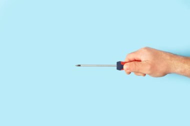 Elinde bir tornavida tutan bir adam açık mavi arka planda fotokopi alanı ile