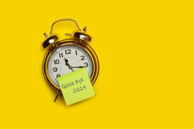 Üzerinde 2024 kısa cümlenin yazılı olduğu yapışkan bir notla birlikte bir çalar saat üzerinde kopya alanı olan sarı bir arkaplan