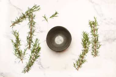 Biberiye dalları ve beyaz mermer mutfak tezgahında boş bir kase.