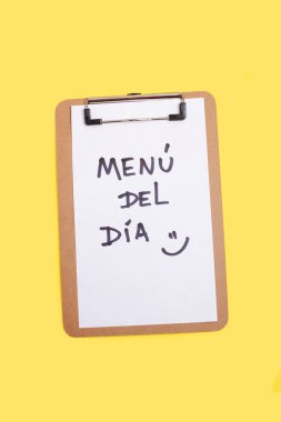 Menü del dia ve sarı arka planda beyaz bir kağıda yazılmış gülen bir surat. Günün menüsü)