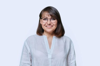 Gülümseyen orta yaşlı bir kadın stüdyonun arka planında kameraya bakıyor. Çekici, mutlu, gözlüklü, dişlek, olgun bir kadın. Başarı, neşe, pozitiflik, yaşam tarzı, 40 'lı yılların insan kavramı