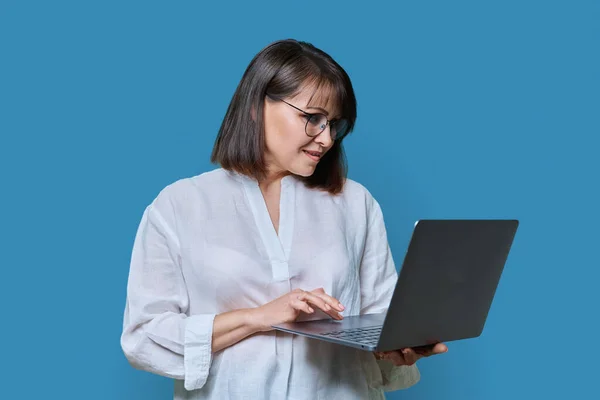 파란색 배경에 랩탑을 여성이 있습니다 안경을 매력적 노트북 화면을 있습니다 — 스톡 사진