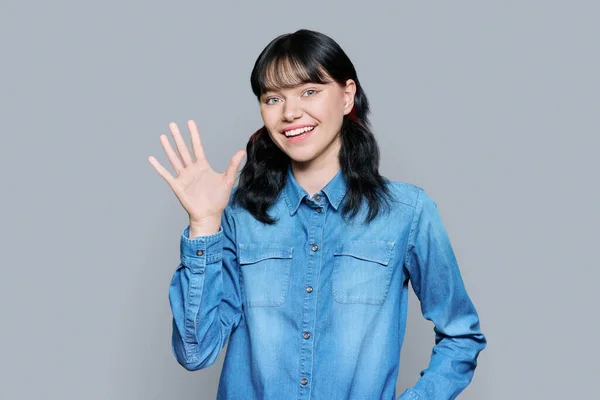 Friendly Teenage Young Woman Looking Camera Waving Hand Greeting Grey — Stock Photo, Image