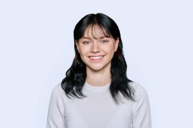 Stüdyonun arka planında kameraya bakan mutlu gülümseyen genç bir kadının portresi. Çekici kız poz veriyor, dişlek gülümsemesiyle. Güzellik, sağlık, yüz bakımı dişleri