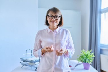 Ofisteki masanın yanında kendine güvenen orta yaşlı bir kadının portresi. Kameraya bakan 40 'lı yılların pozitif iş kadını yönetici öğretmen akıl hocası. Uzaktan çalışma serbest kariyer personeli