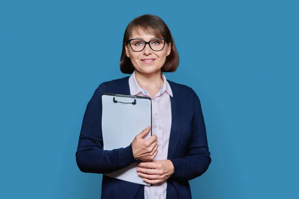 Middle Age Business Woman Clipboard Looking Camera Blue Studio Background — Stock Photo, Image