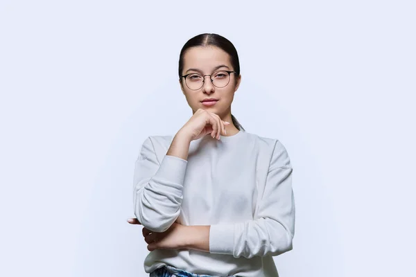 戴眼镜的少女在白色摄影棚的背景下看着摄像机 聪明学生14 15岁的画像 青春期 生活方式 情感教育概念 — 图库照片