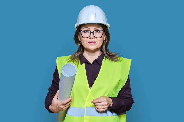 Woman engineer architect with construction drawing rolled up blueprint in helmet protective vest looking at camera on white studio background. Construction, architecture engineering concept