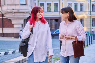 İki nesil, neşeli, mutlu anne ve şık, çekici genç kız şehir caddesinde birlikte yürüyüp konuşuyorlar. Aile içi iletişim, ebeveyn, çocuk, genç yaşam tarzı, boş insanlar.