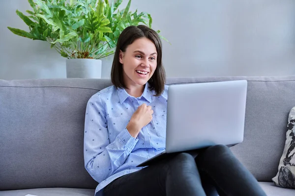 美しい若い女性がビデオ会議のチャットコールのためのラップトップを使用しています ホーム テクノロジー レジャー ライフスタイルの若者の概念でソファに座っている画面の女性を見て笑う — ストック写真