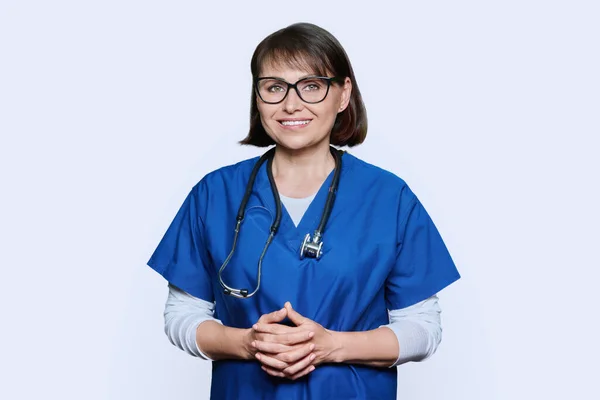 中年医生面带微笑的画像 带着听诊器 在白色的工作室背景上看着相机 带着一副眼镜 带着灿烂笑容的女护士是积极的 医疗护理人员医疗服务 — 图库照片