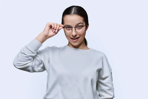 十几岁的女生拿着眼镜微笑着看着镜头在白色的工作室背景 青春期 生活方式 情感教育概念 — 图库照片