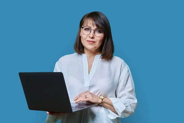 Ältere Geschäftsfrau Mit Laptop Auf Blauem Studiohintergrund Lächelt Selbstbewusst Die — Stockfoto