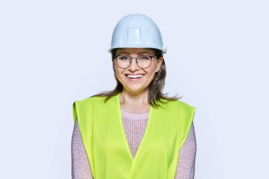Beyaz arka planda kameraya bakan çelik yelekli, gülümseyen kadın sanayi işçisinin portresi. Lojistik inşaat endüstrisi yönetim mimari mühendislik personel kavramı