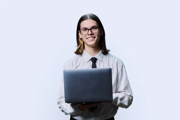 Handsome young male using laptop on light studio background. Positive smiling guy in white business shirt and tie looking at camera. Business, education, technology, communication, people concept