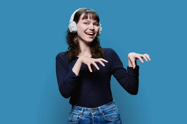 快乐迷人的年轻女性在耳机跳舞流行的舞蹈 蓝色工作室背景 现代青年 生活方式 人的观念 — 图库照片