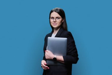 Portrait of smiling young business woman with laptop, confident female looking at camera on blue color background. 30s female manager banker mentor using pc for e-learning remote work online service
