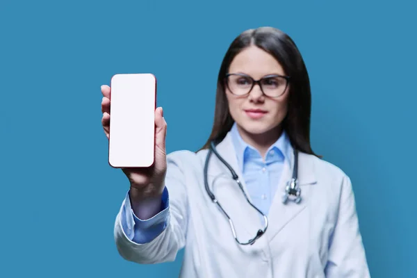 Close Smartphone Branco Nas Mãos Uma Médica Fundo Estúdio Azul — Fotografia de Stock