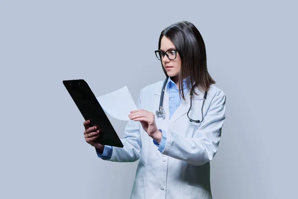 Young Friendly Woman Doctor Clipboard Light Gray Studio Background Confident — Stock Photo, Image