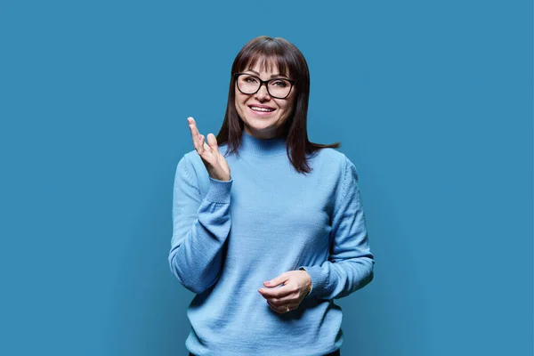 Mavi Arka Planda Kazak Giymiş Gözlüklü Olgun Bir Kadının Portresi — Stok fotoğraf