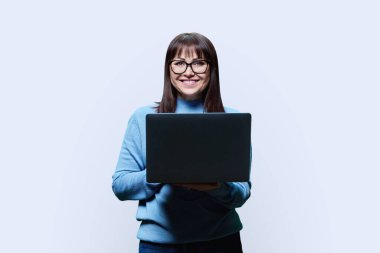 Dost canlısı, olgun bir kadın, beyaz stüdyo geçmişi üzerinden dizüstü bilgisayar kullanıyor. Sıradan kazaklı, gülümseyen orta yaşlı bir kadın kameraya bakıyor. İş, personel, serbest çalışma, teknoloji yaşam tarzı eğlence konsepti