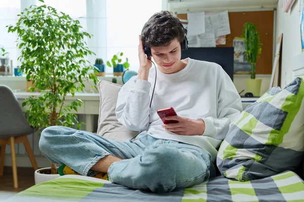 Hombre Joven Auriculares Mirando Teléfono Inteligente Mientras Está Sentado Sofá — Foto de Stock