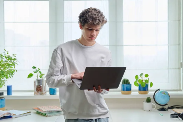 一个拿着笔记本电脑的认真的大学生的画像 在家里 20岁的英俊男性使用笔记本电脑 在线互联网技术远程电子学习研究休闲通信 — 图库照片