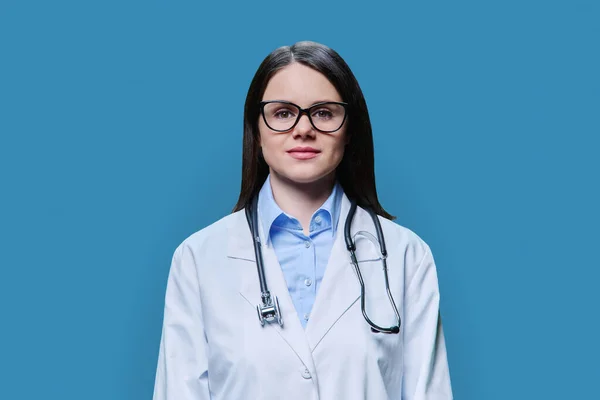 身穿白衣的严肃女医生的画像 用蓝色背景的相机看着 医务人员 科学医学概念 — 图库照片