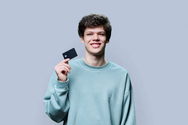 Junger Gutaussehender Kerl Mit Kreditkarte Der Hand Vor Grauem Studiohintergrund — Stockfoto