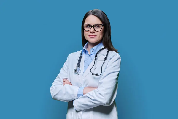 身穿白衣 双手交叉 面带微笑 自信的女医生形象 在蓝色工作室背景下看着相机 医务人员 科学医学概念 — 图库照片