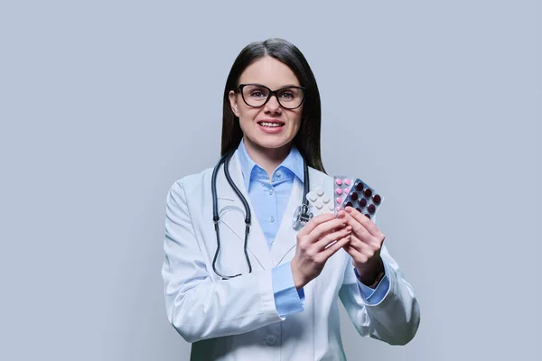 Giovane Medico Donna Raccomanda Diverse Pillole Blister Sfondo Grigio Chiaro — Foto Stock