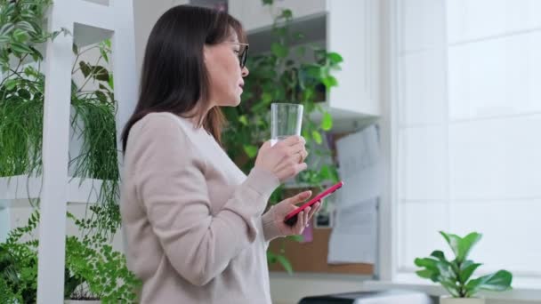 Donna Mezza Età Con Bicchiere Acqua Utilizzando Smartphone Interni Casa — Video Stock