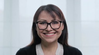 Gözlüklü, dişleriyle gülümseyen güzel, olgun bir kadının yüz portresi. Kameraya bakan orta yaşlı bir kadın. Duygular başarı mutluluk ifadesi, güzellik, sağlık 40 'lar