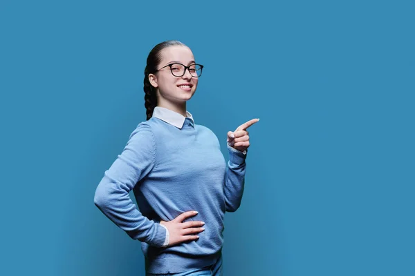 Дівчинка Підліток Вказує Пальцем Порожнє Місце Тексту Синій Студійний Фон — стокове фото