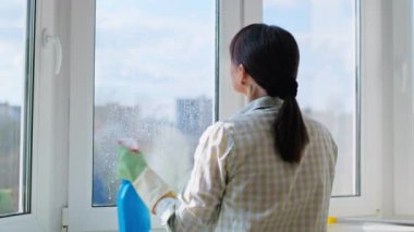 Evdeki pencereleri sprey ve mikrofiber bez kullanarak temizleyen kadın. Ev temizliği, ev işi, temizlik, iş, hizmet kavramı