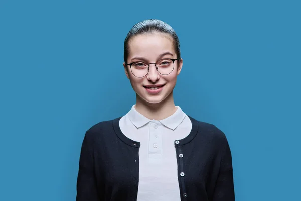在蓝色工作室背景的快乐高中女生的特写 戴着眼镜的少女带着牙齿微笑 看着相机 青春期 生活方式教育 休闲青少年 — 图库照片