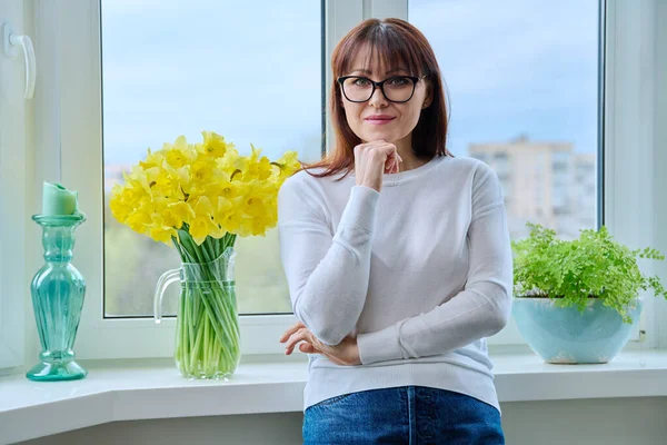 Mujer Sonriente Mediana Edad Mirando Cámara Cerca Ventana Casa Ramo —  Fotos de Stock