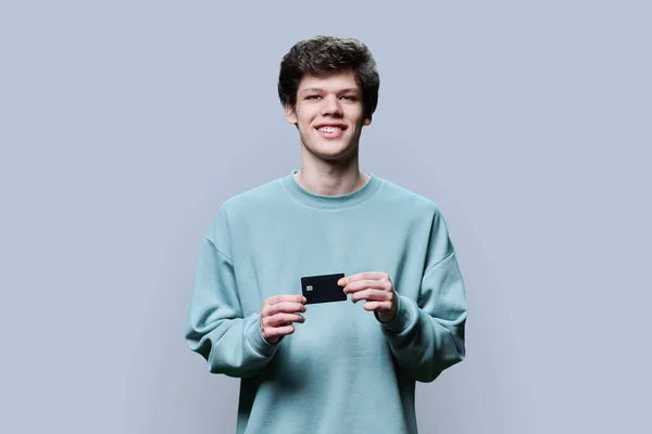 Junger Gutaussehender Kerl Mit Kreditkarte Der Hand Vor Grauem Studiohintergrund — Stockfoto