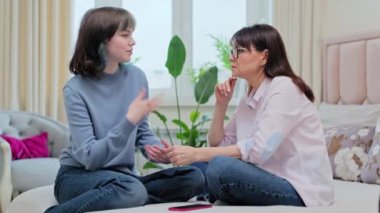 Orta yaşlı, dost canlısı anne ve genç kız 18-19 yaşlarında. Kanepe yatağında birlikte oturuyorlar. Aile içi ilişkiler, ebeveyn, ebeveyn desteği, arkadaşlık kavramı.