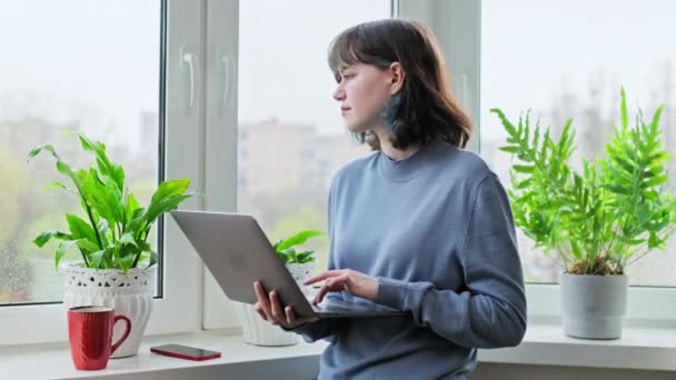 迷人的18 19岁的年轻女性在家里靠窗的地方使用笔记本电脑 用于休闲学习交流的在线互联网技术 — 图库视频影像