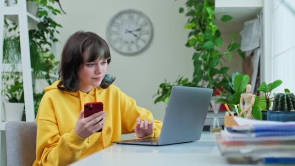 Νεαρή Γυναίκα Ετών Κάθεται Στο Τραπέζι Στο Σπίτι Χρησιμοποιώντας Smartphone — Αρχείο Βίντεο