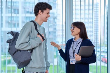 Toplantı, koridor eğitim merkezinin penceresinin yanında kadın öğretmen ve erkek üniversite öğrencisinin konuşması. Konuşan kadın eğitmen pedagog öğretmeni ve genç bir erkek. Eğitim, öğrenme, öğrenme